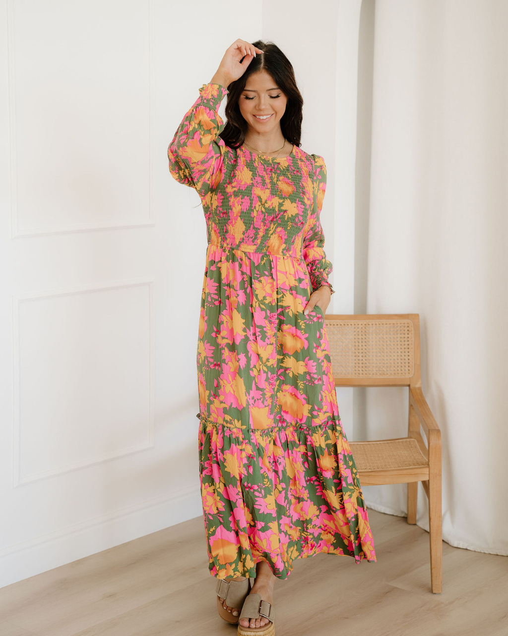 Close-up of a women's orange floral maxi dress featuring a smocked bodice, short puff sleeves, and a tiered frill skirt layout.