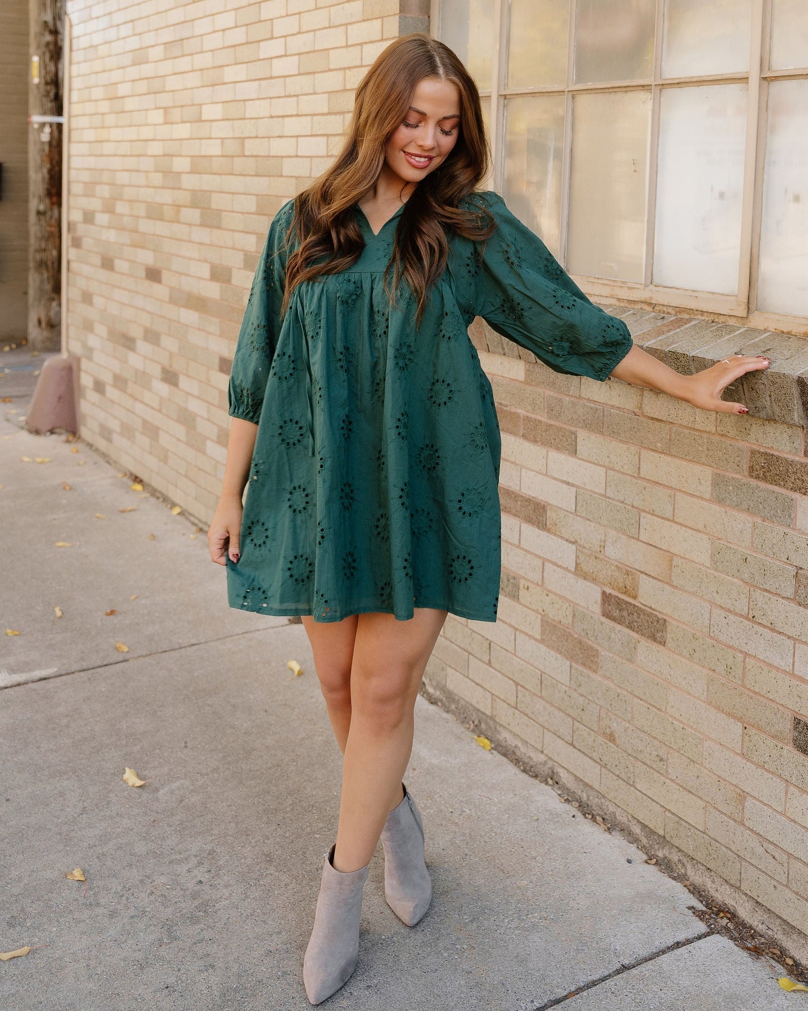 Front view of the Sybil eyelet mini dress in deep blackish green, showcasing the detailed cotton eyelet pattern and dramatic puff sleeves.