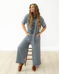 Front view of a women's short-sleeve jumpsuit in Beau Blue, highlighting front patch pockets, a subtle colorblock design, and a relaxed, comfortable silhouette.