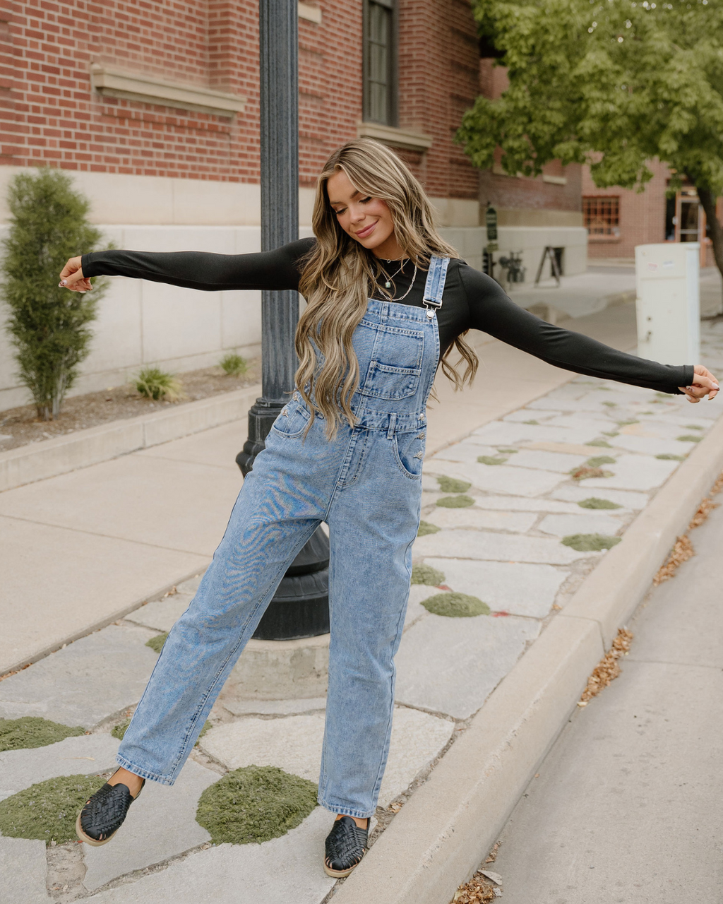 Women's sail blue denim bib overalls featuring a straight-leg silhouette, classic pocket details, and adjustable straps.