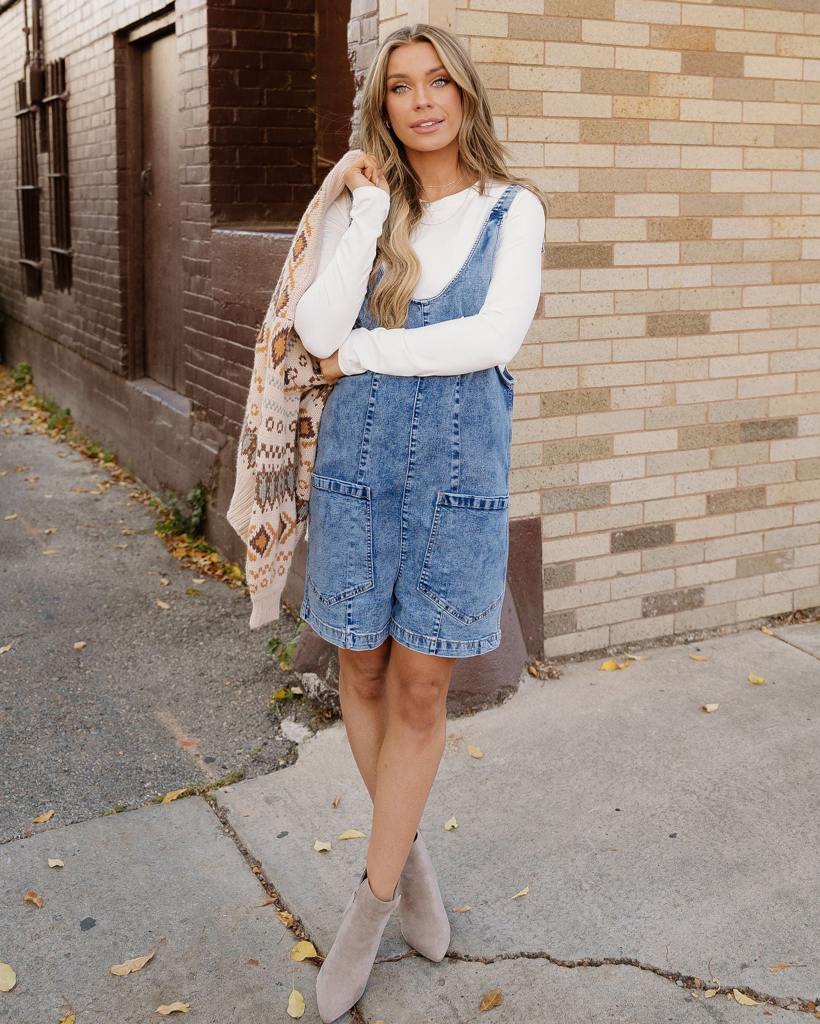 Front view of the Jett casual sleeveless denim romper in Dusk Blue, showcasing its deep U-neckline, front utility pockets, and comfortable short silhouette.