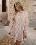 A woman wearing the Dallas brown striped mini dress featuring a collared neckline, button-down front, side pockets, and a tiered ruffle hem.
