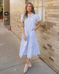 Front view of a women's tiered midi dress in a sky blue and white stripe pattern, highlighting the puff sleeves and intricate scalloped detailing along each tier.