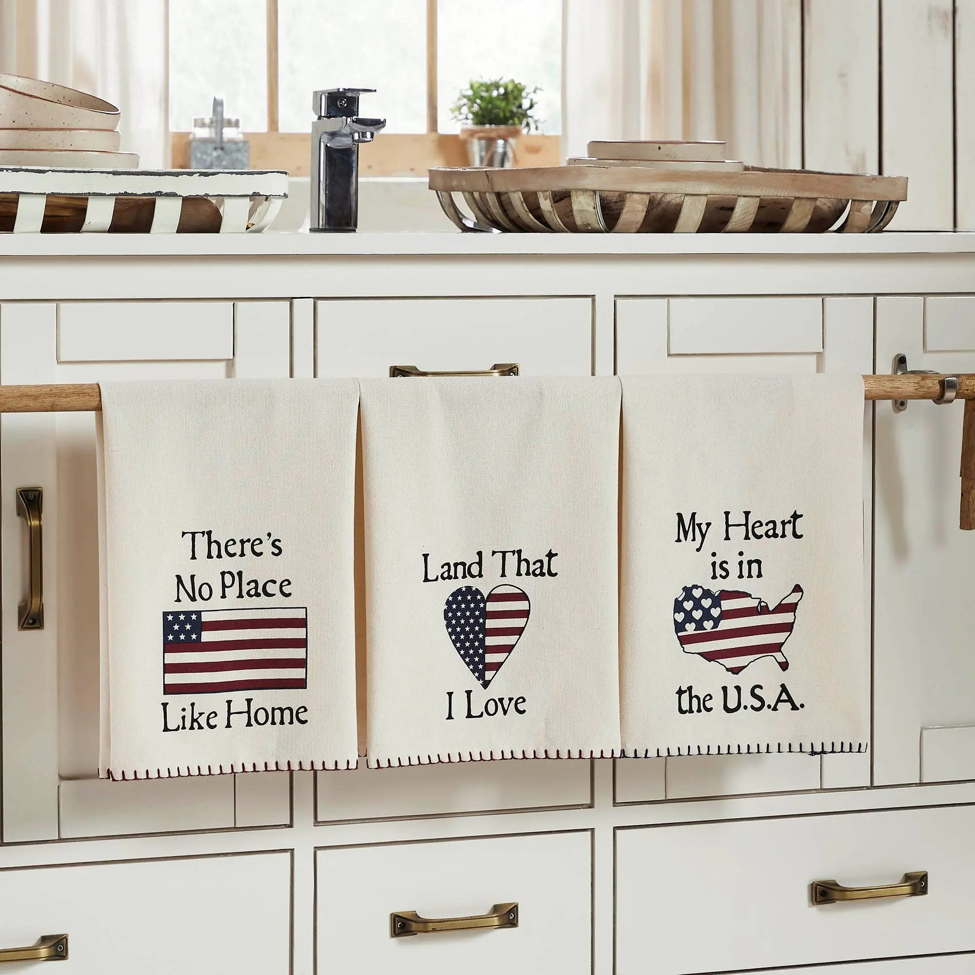 Set of three ivory tea towels with patriotic designs including a flag heart, USA map, and 'There's No Place Like Home' text
