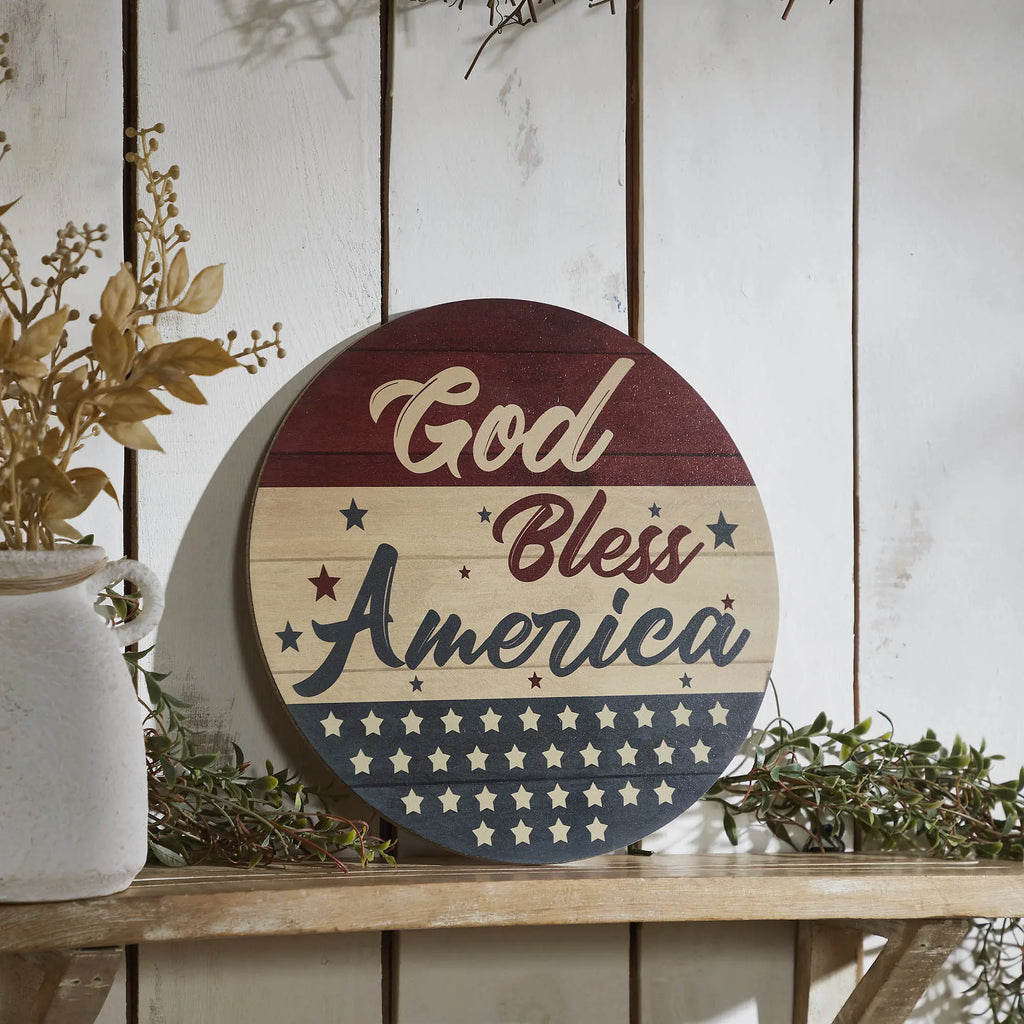 Round 11-inch patriotic welcome sign with stars and stripes in burgundy, navy, and cream with a distressed finish.