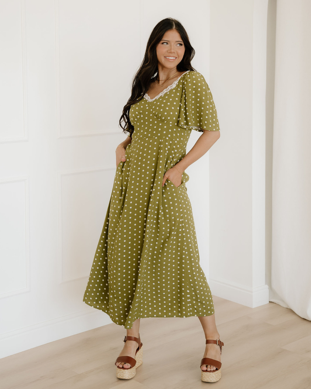 Women's green polka dot maxi dress featuring a vintage-inspired lacy neckline, a smocked high-waisted bodice, and a flowy long tiered skirt layout.