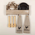 Set of two khaki cotton tea towels featuring a black stenciled rooster and a ticking stripe ruffle border.