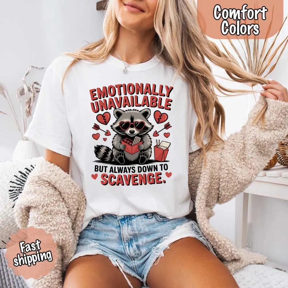 Vintage-style graphic of a moody-looking raccoon with the text 'Emotionally Unavailable' on a garment-dyed Comfort Colors t-shirt."