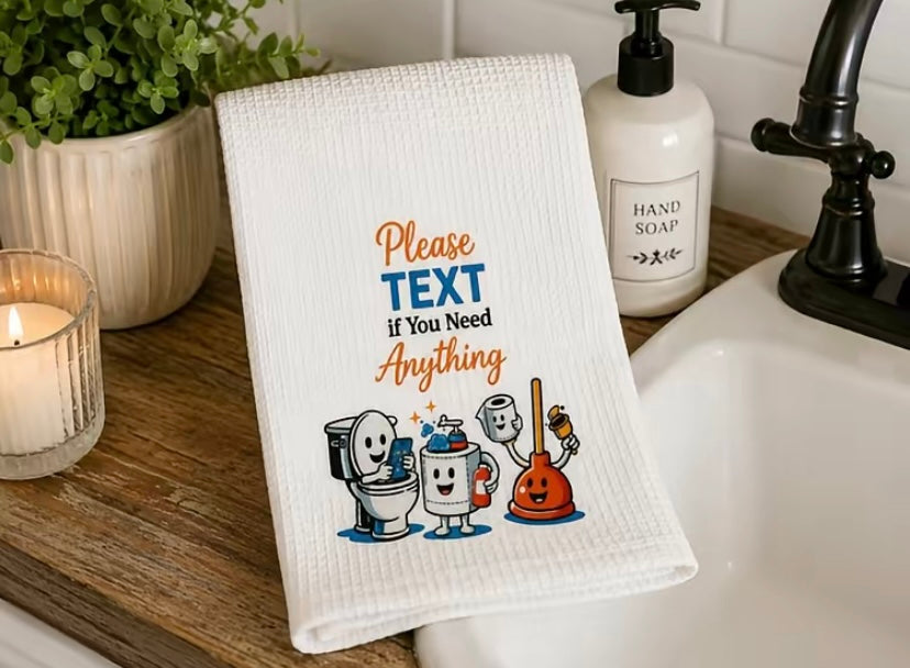16x28 white microfiber hand towel with 'Please TEXT If You Need Anything' funny text displayed next to a soap dispenser by the bathroom sink