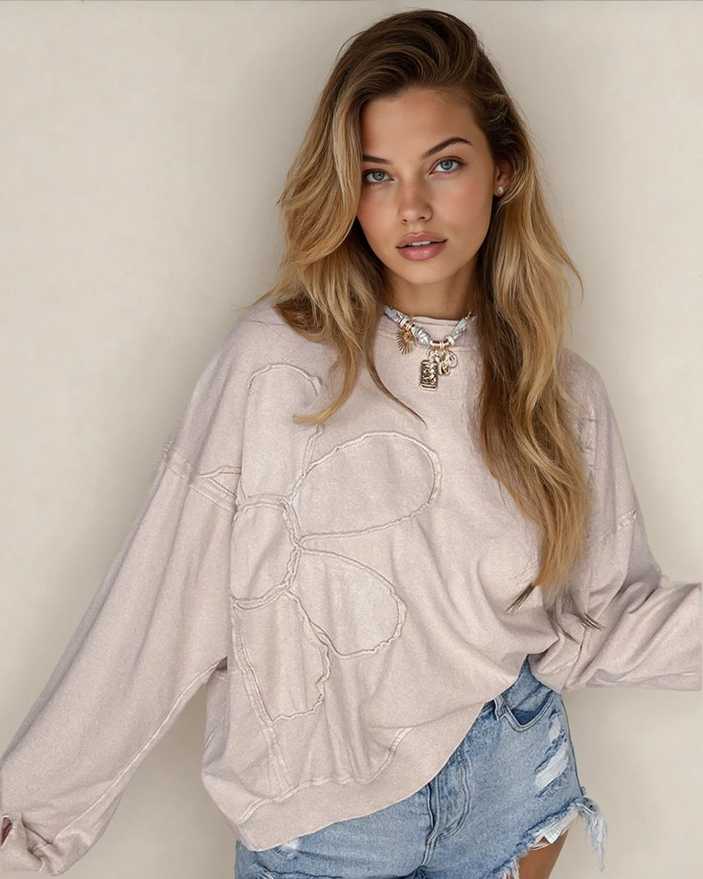 Front view of the relaxed-fit Luna floral top in beige, featuring long sleeves, drop shoulders, a round neckline, and modern raw-edge seam detailing.