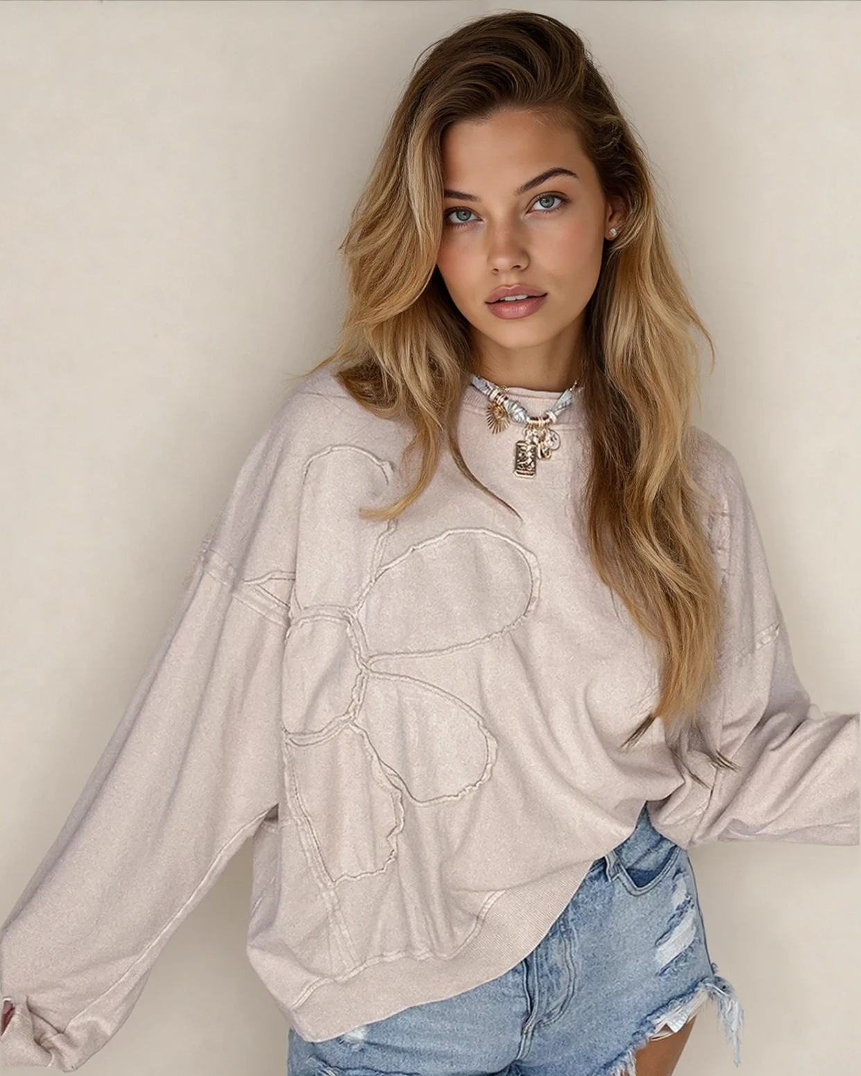 Front view of the relaxed-fit Luna floral top in beige, featuring long sleeves, drop shoulders, a round neckline, and modern raw-edge seam detailing.