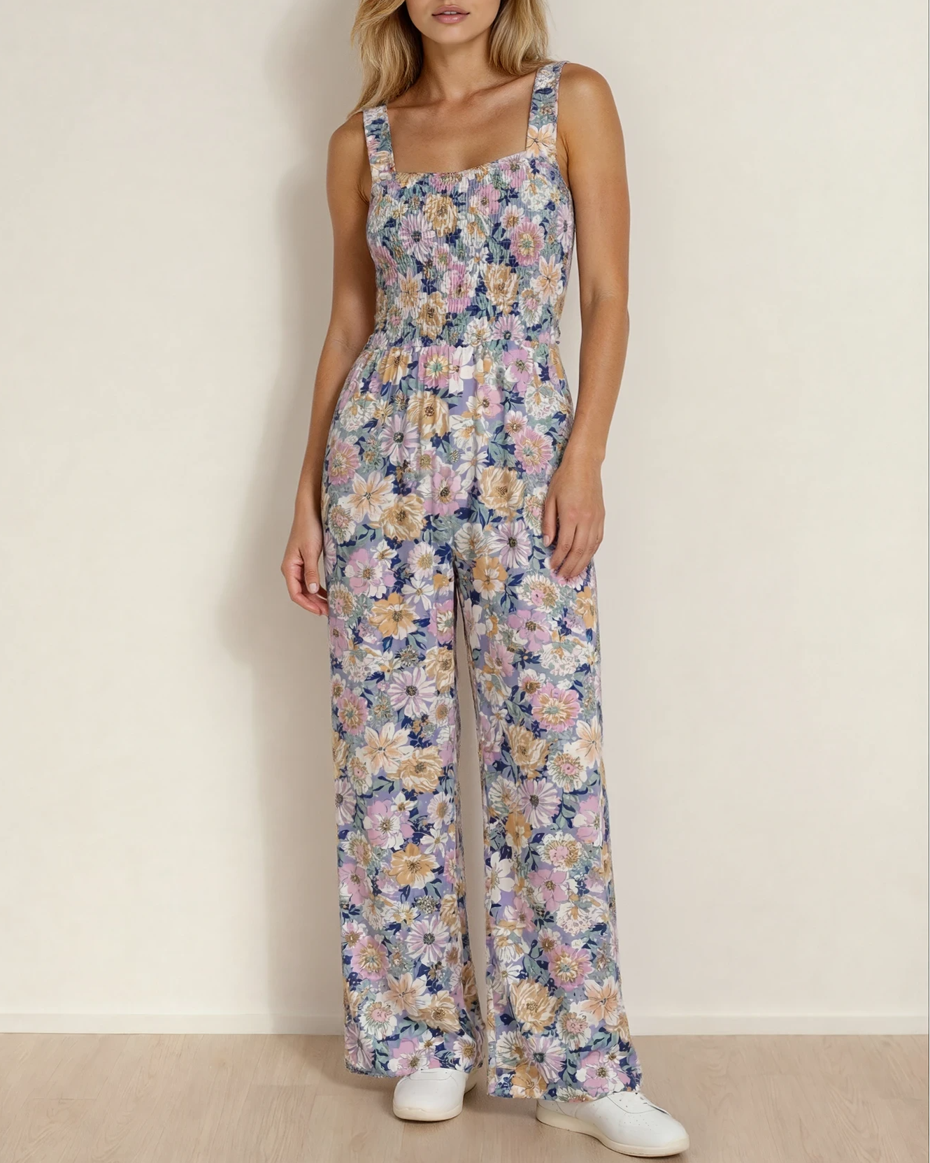 A woman wearing a sleeveless purple boho floral high-waist jumpsuit featuring a square neckline and a comfortable stretch bodice.