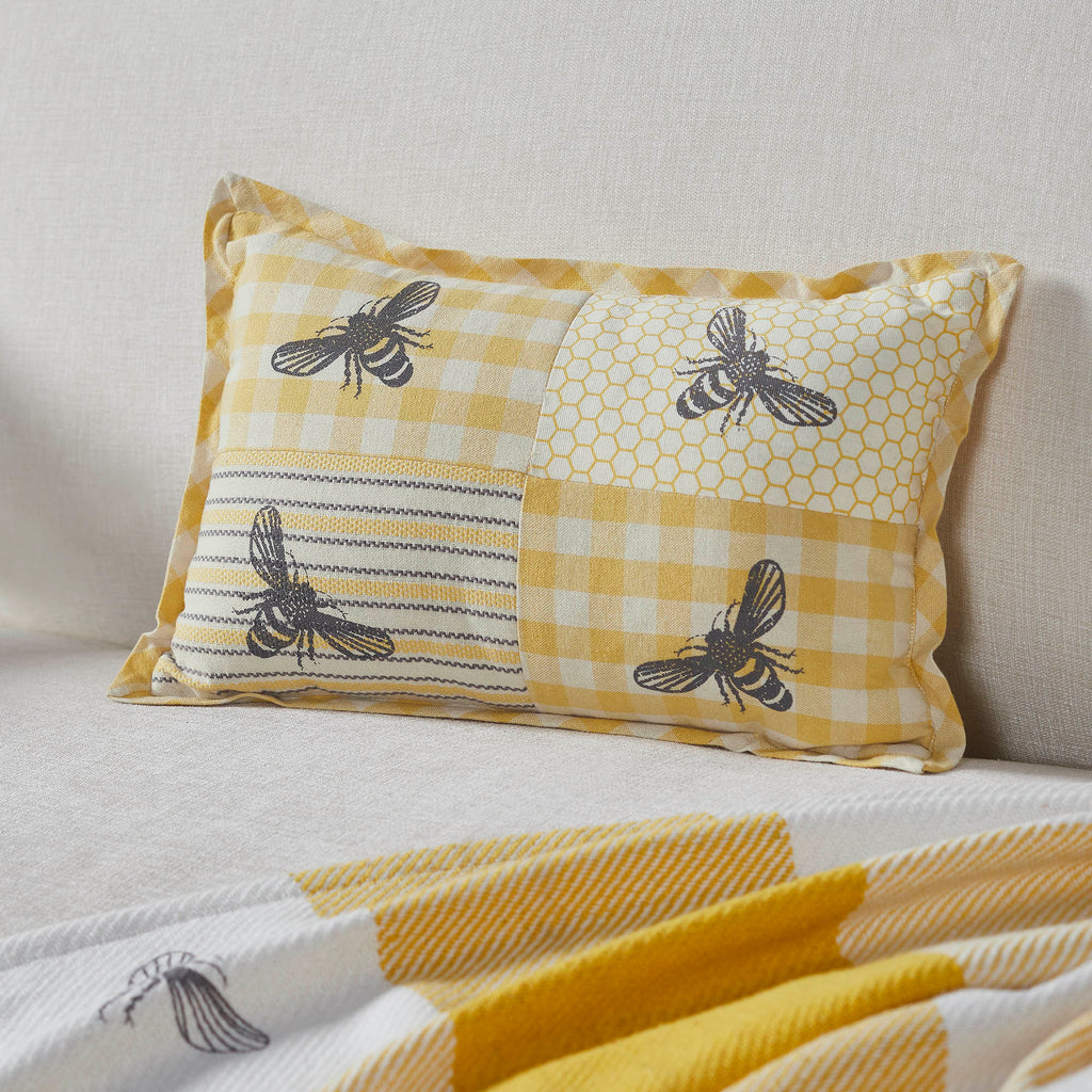 Yellow patchwork bee lumbar accent pillow featuring gingham, honeycomb and vintage bee prints measuring 9.5 x 14 inches.