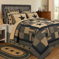 Close-up of a premium black star primitive patchwork quilt showing detailed hand-quilting, textured charcoal and cream cotton fabrics.