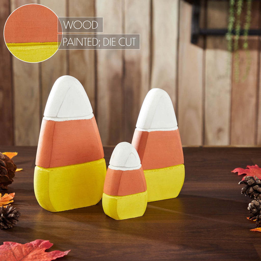 Wooden candy corn set styled on a dark wood background with autumn foliage.