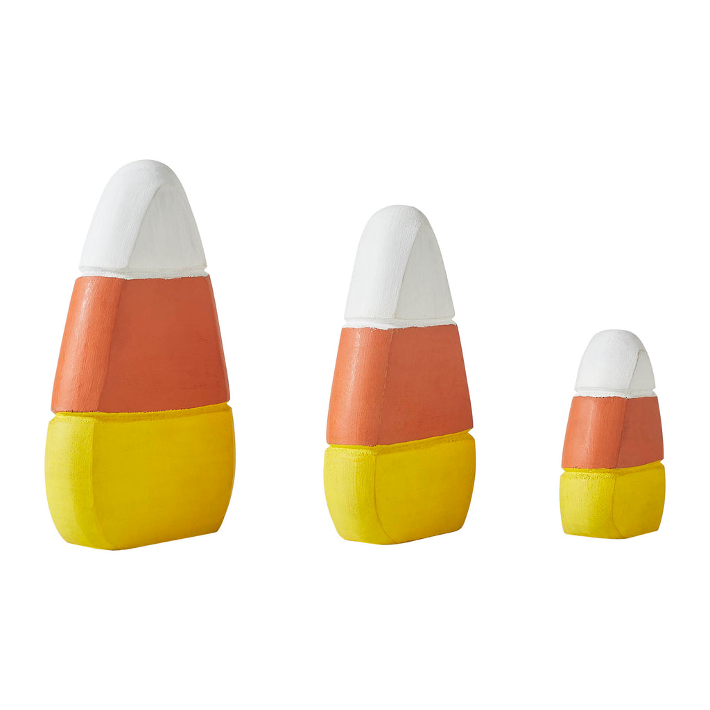 Close-up detail of three wooden candy corn figurines standing on a flat surface.