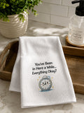 Folded white hand towel displayed in a bathroom setting featuring printed black text reading 'You've Been in Here a While... Everything Okay?' next to a small alarm clock graphic.