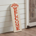 Vertical wooden Fall Welcome porch sign with ornate scrolling top leaning beside a front door entry.