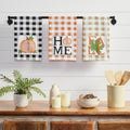 Set of three farmhouse fall kitchen towels featuring buffalo check patterns with pumpkin, HOME, and FALL designs on 100% cotton muslin fabric.