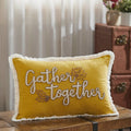 Gather Together embroidered yellow velvet throw pillow displayed on a brown leather bench in a rustic living room.