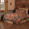Rustic Maisie patchwork queen quilt in red, brown, and tan plaid pattern styled on a wooden frame bed with matching shams.
