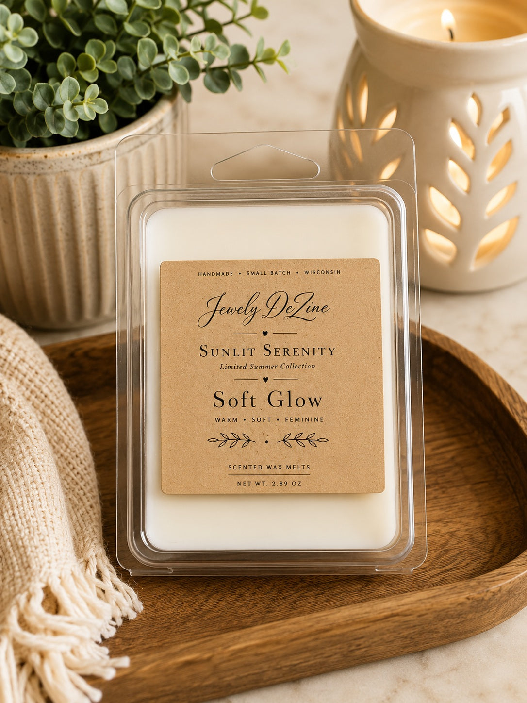 Package of Soft Glow soy wax melts sitting next to a glowing ceramic wax warmer and a small potted plant on a decorative tray.