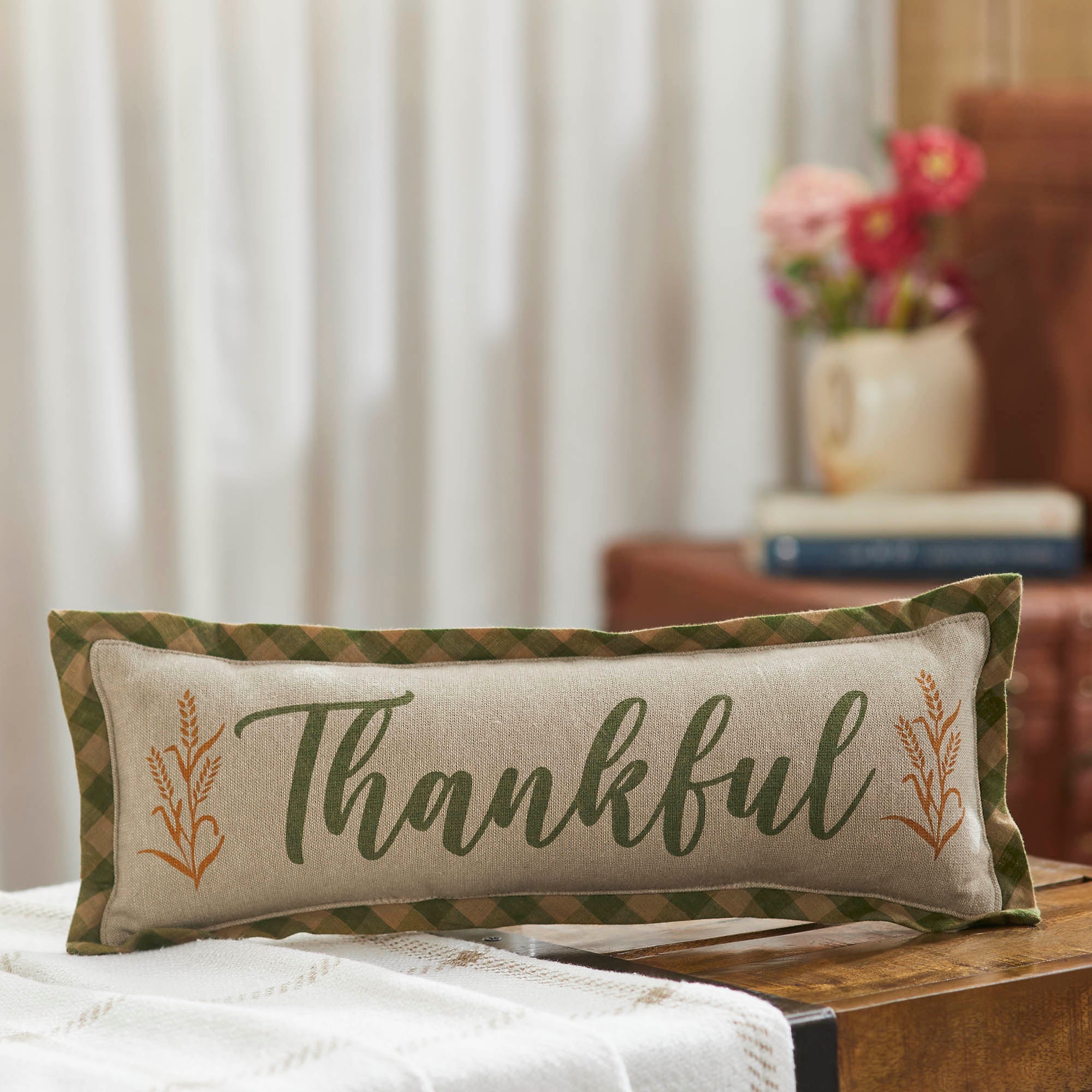 Decorative lumbar accent pillow with 'Thankful' text displayed on a cozy tabletop.